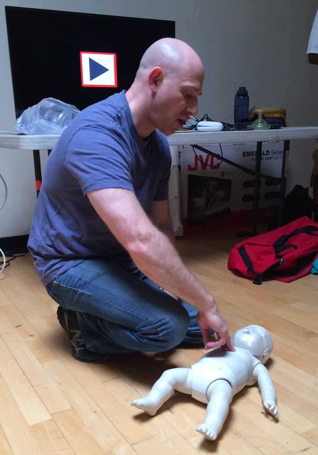 Josh Sauberman instructing CPR with an infant manikin.